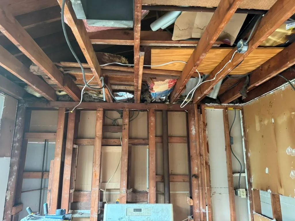 Interior framing with wooden beams, electrical wiring, and exposed stud walls during renovation